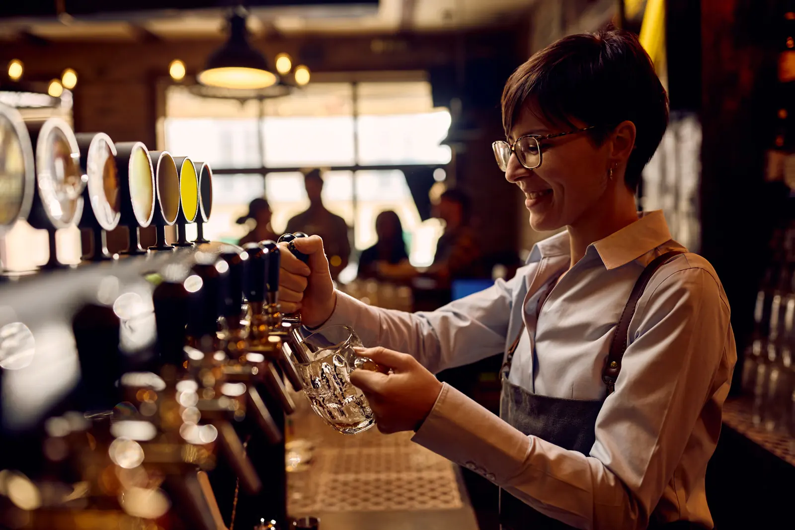 A bartender pours a beer mid-shift